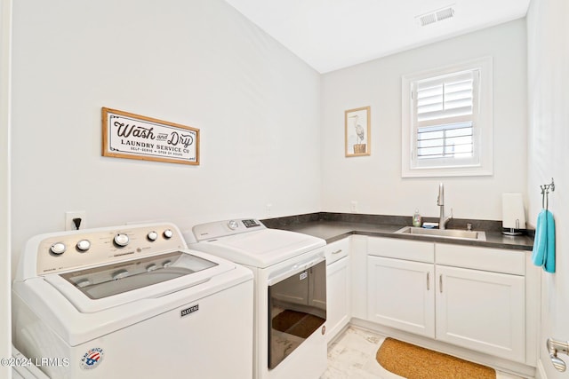 clothes washing area featuring cabinets, washing machine and dryer, and sink