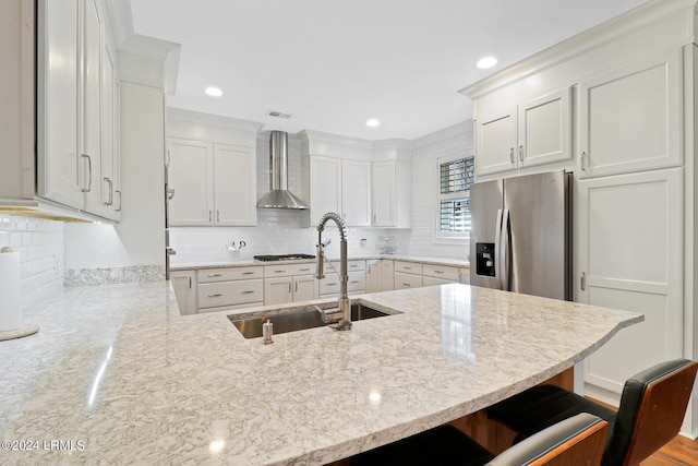 kitchen with sink, a kitchen bar, stainless steel fridge with ice dispenser, kitchen peninsula, and wall chimney exhaust hood