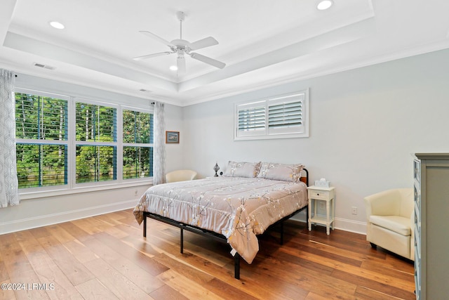 bedroom with ceiling fan, ornamental molding, a raised ceiling, and hardwood / wood-style floors