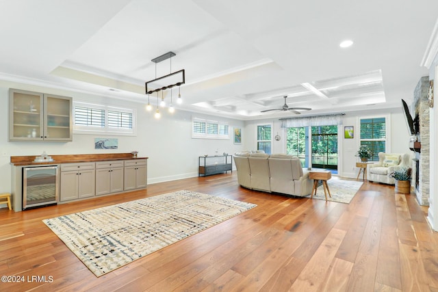 living room with light wood-type flooring, wine cooler, coffered ceiling, bar, and beam ceiling