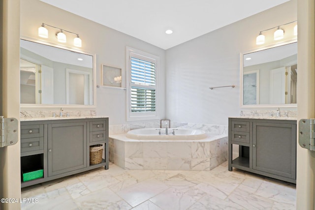 bathroom featuring tiled tub and vanity