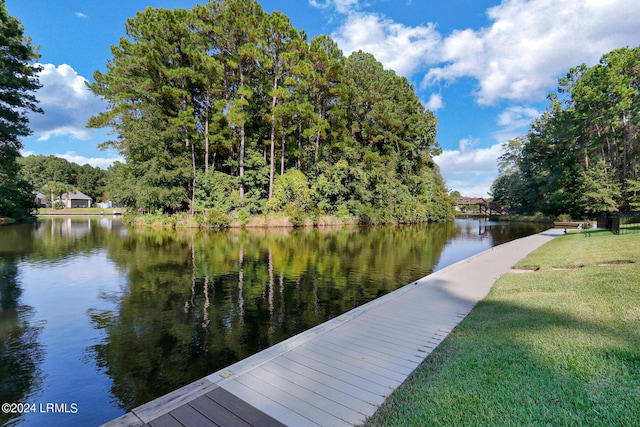 view of dock with a yard and a water view