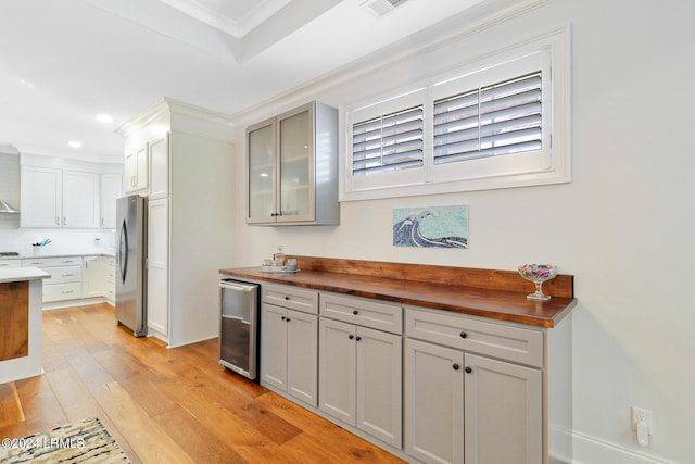 kitchen featuring wine cooler, wood counters, tasteful backsplash, stainless steel refrigerator, and ornamental molding