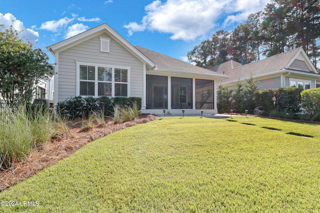 back of property featuring a sunroom and a lawn