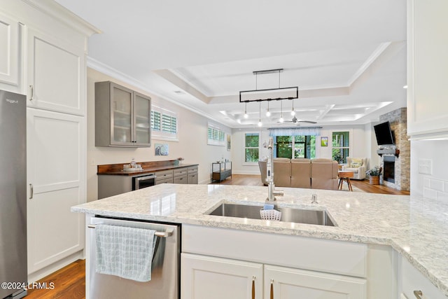 kitchen with a fireplace, light stone countertops, light hardwood / wood-style floors, and appliances with stainless steel finishes