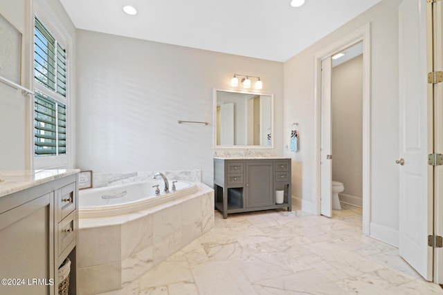 bathroom with vanity, tiled bath, and toilet