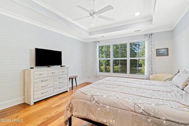 bedroom with hardwood / wood-style floors, crown molding, a raised ceiling, and ceiling fan