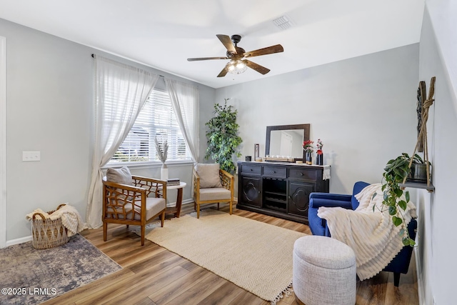 sitting room with a ceiling fan, baseboards, visible vents, and wood finished floors