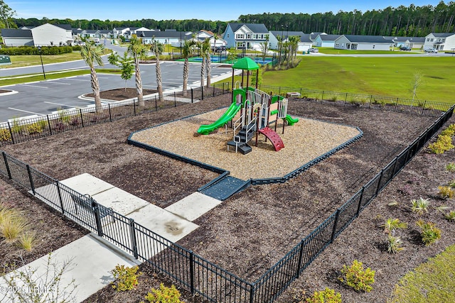 community jungle gym featuring a lawn, fence, and a residential view