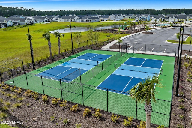 view of sport court featuring a water view, fence, and a residential view