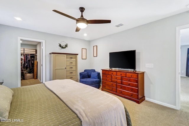 carpeted bedroom featuring a walk in closet, recessed lighting, visible vents, a ceiling fan, and baseboards