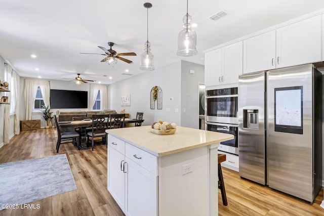 kitchen featuring visible vents, appliances with stainless steel finishes, a center island, light wood-style floors, and white cabinetry