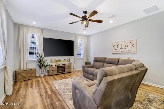 living area with baseboards, wood finished floors, visible vents, and a ceiling fan