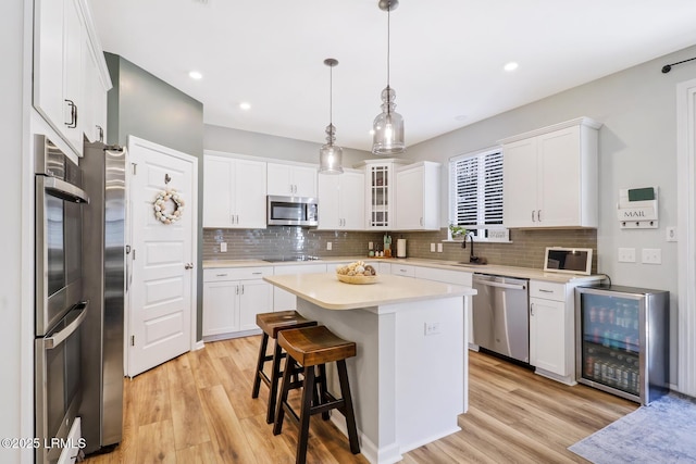 kitchen featuring white cabinetry, appliances with stainless steel finishes, light countertops, and a sink