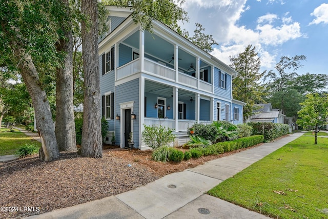 view of front facade with a porch, a balcony, a front yard, and ceiling fan