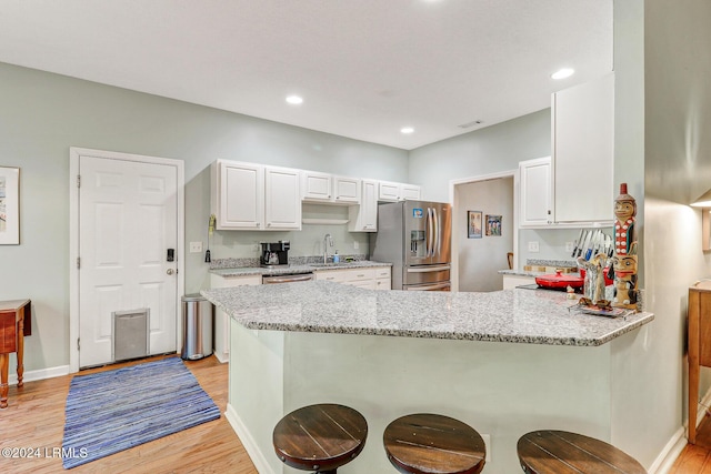 kitchen with light stone counters, white cabinetry, appliances with stainless steel finishes, and kitchen peninsula