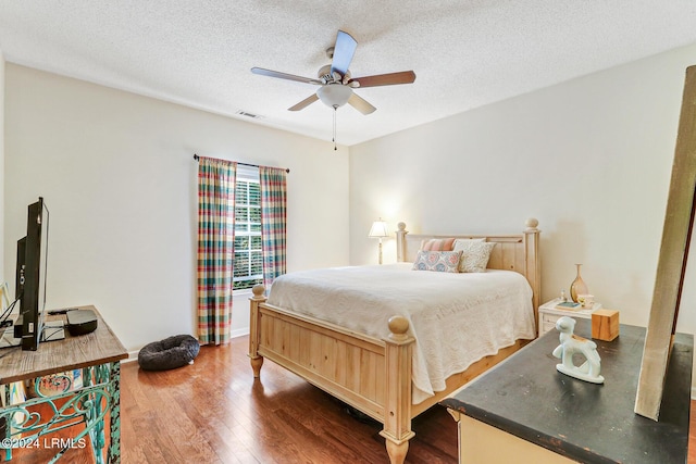 bedroom featuring dark wood-type flooring, ceiling fan, and a textured ceiling