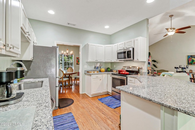 kitchen with stainless steel appliances, light stone counters, light hardwood / wood-style floors, white cabinets, and ceiling fan with notable chandelier