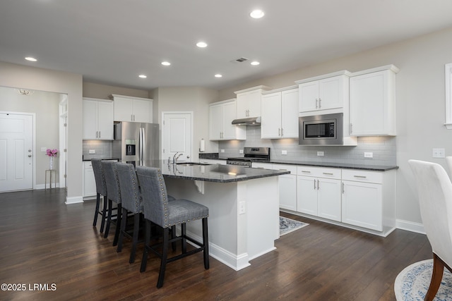 145 Rudder Run, Bluffton, SC 29910 - kitchen with appliances with stainless steel finishes, under cabinet range hood, a kitchen bar, dark wood-style floors, and decorative backsplash