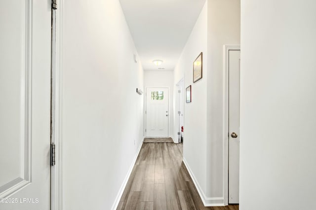 corridor featuring baseboards and dark wood-type flooring