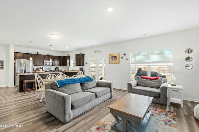 living room with french doors, light wood-type flooring, and baseboards