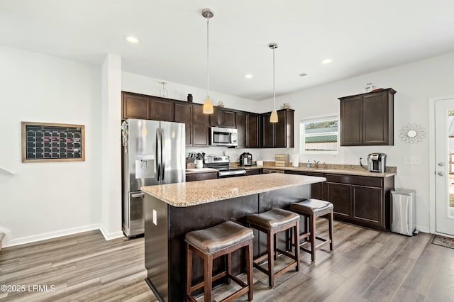 kitchen with a sink, light wood-type flooring, stainless steel appliances, and dark brown cabinets