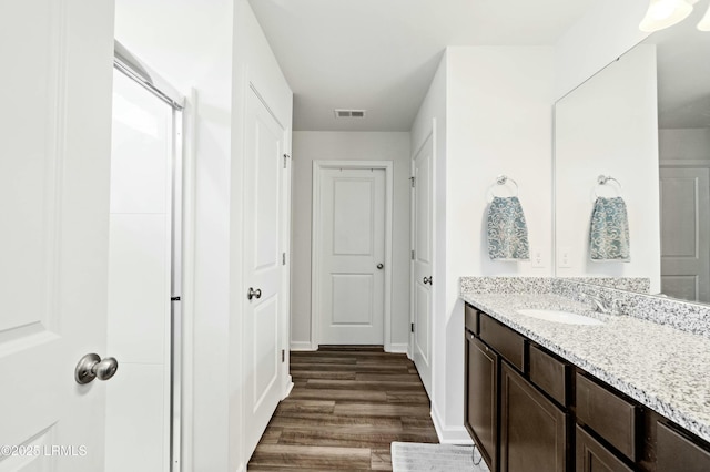 bathroom featuring baseboards, visible vents, wood finished floors, and vanity