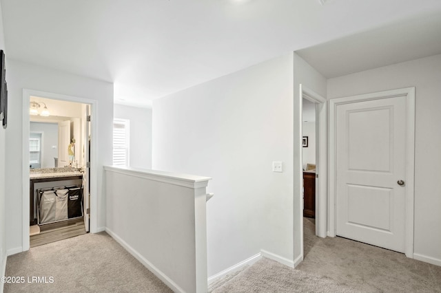 hall with carpet floors, baseboards, and an upstairs landing