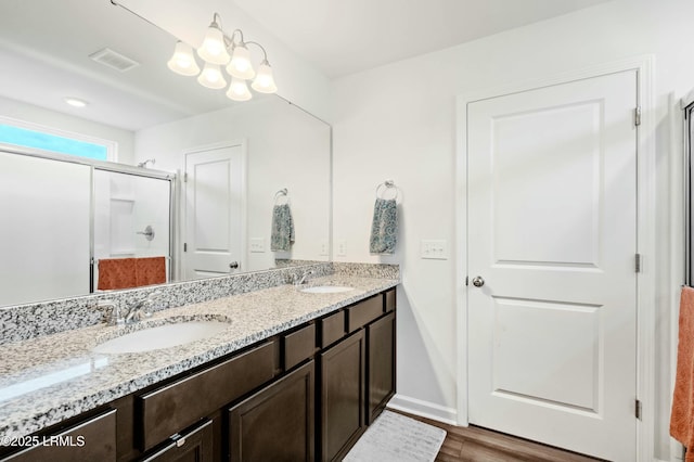 full bathroom featuring visible vents, a sink, a shower stall, and double vanity