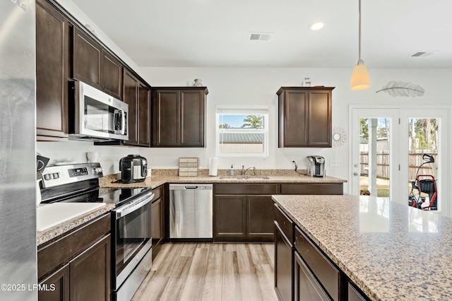 kitchen with light wood-style flooring, dark brown cabinetry, a sink, visible vents, and appliances with stainless steel finishes