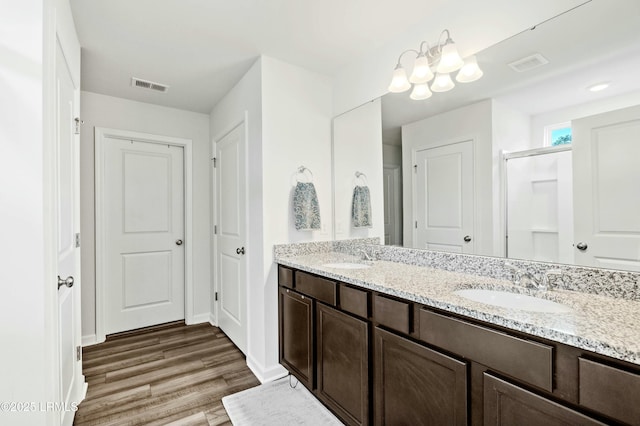 bathroom featuring double vanity, wood finished floors, a sink, and visible vents