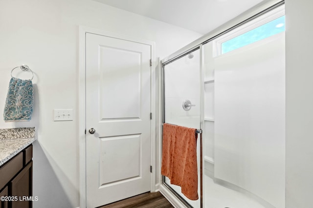 full bathroom with a stall shower, vanity, and wood finished floors