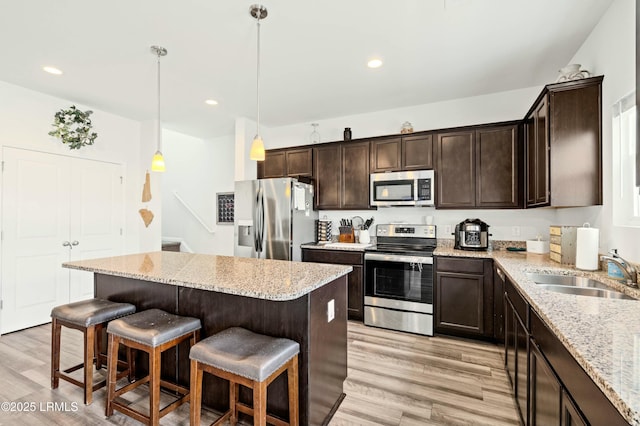 kitchen featuring light wood-style flooring, a kitchen bar, appliances with stainless steel finishes, and a sink