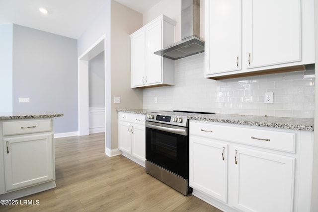 kitchen with white cabinetry, light wood-style floors, backsplash, stainless steel electric stove, and wall chimney exhaust hood