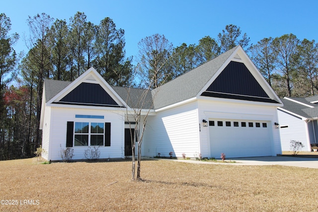 view of front of house with concrete driveway, roof with shingles, an attached garage, board and batten siding, and a front yard