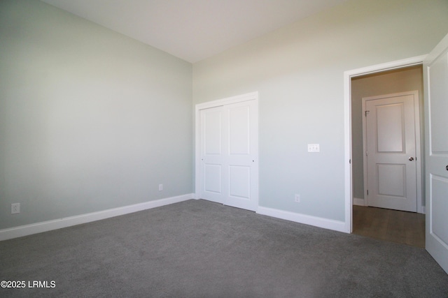 unfurnished bedroom with baseboards, dark colored carpet, and a closet