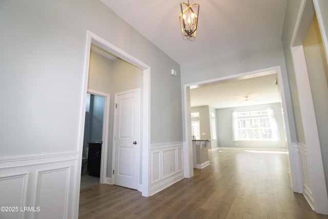 hall featuring a wainscoted wall, an inviting chandelier, wood finished floors, and a decorative wall