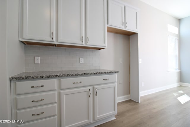 kitchen featuring white cabinets, light wood finished floors, decorative backsplash, and light stone countertops