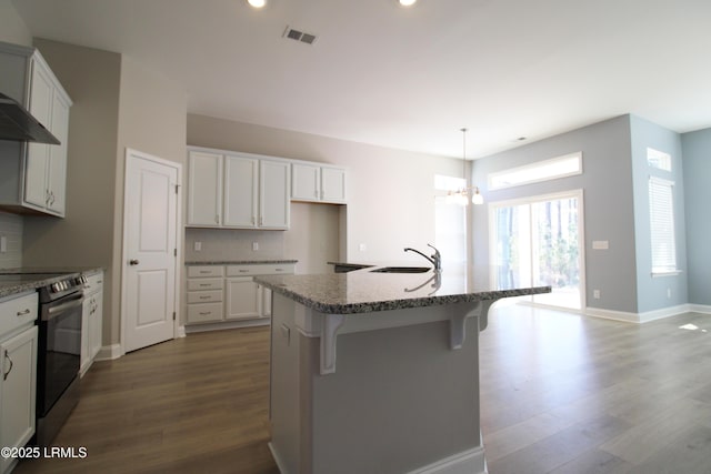 kitchen featuring dark wood-style floors, tasteful backsplash, visible vents, electric range oven, and a sink