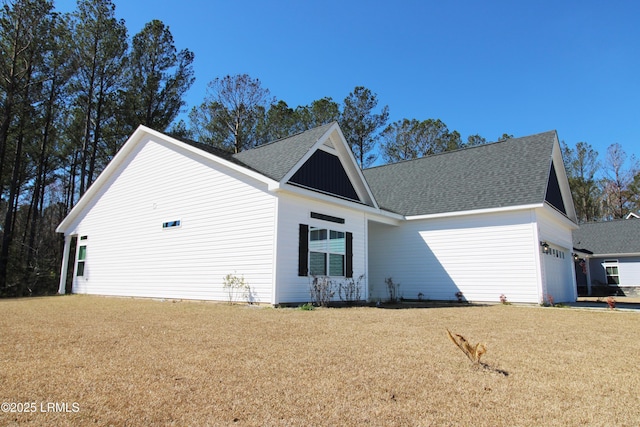 view of front of house with a garage, a front lawn, and a shingled roof