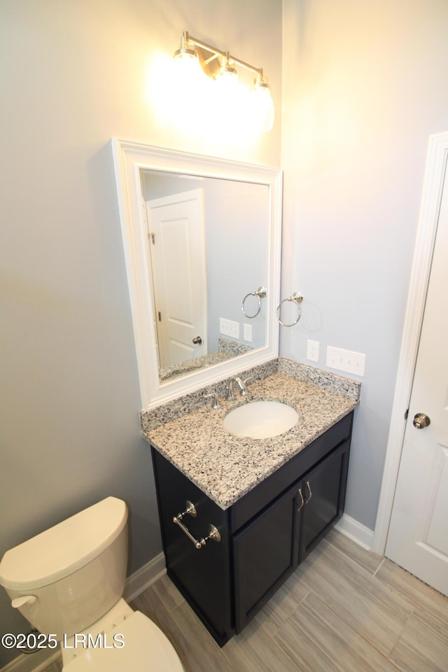 bathroom featuring toilet, vanity, and baseboards