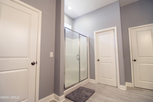 bathroom with a stall shower, baseboards, and wood tiled floor