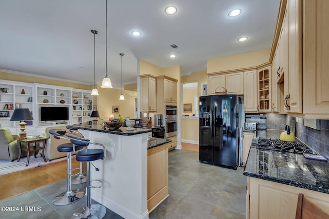 kitchen featuring appliances with stainless steel finishes, a breakfast bar area, light brown cabinetry, and decorative light fixtures