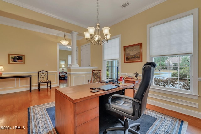 office space featuring ornate columns, crown molding, a chandelier, and light hardwood / wood-style floors