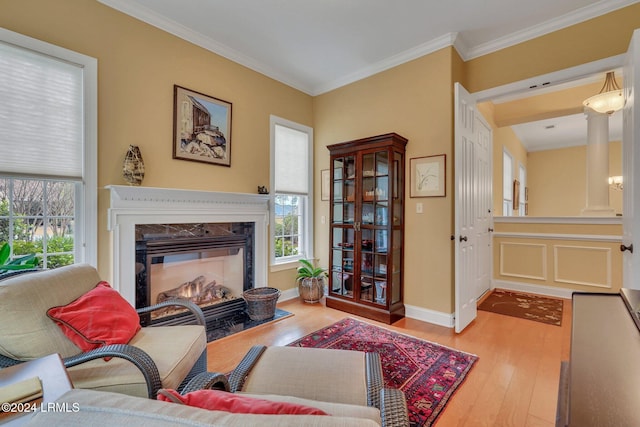 living room featuring a high end fireplace, light hardwood / wood-style flooring, ornamental molding, and a healthy amount of sunlight