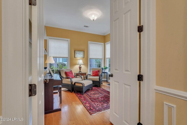 living area featuring light hardwood / wood-style flooring and ornamental molding