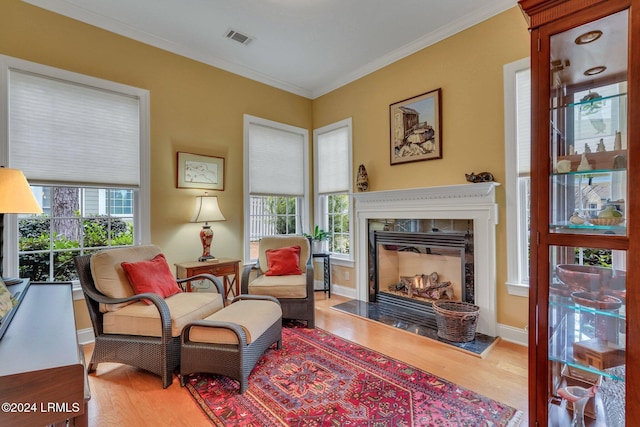 living area with hardwood / wood-style flooring, a high end fireplace, and crown molding