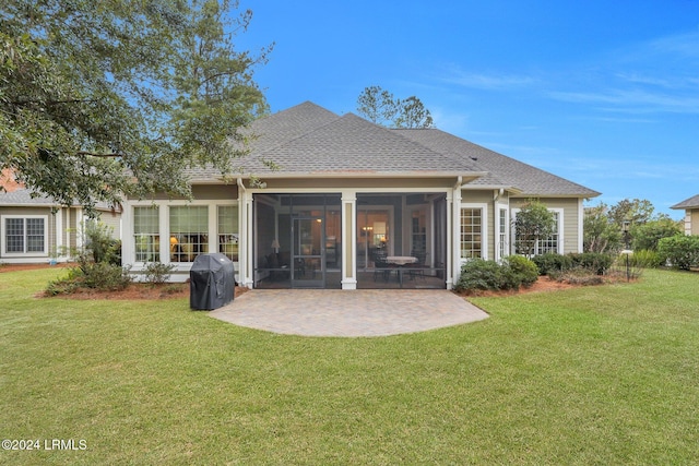 rear view of property featuring a patio, a sunroom, and a lawn