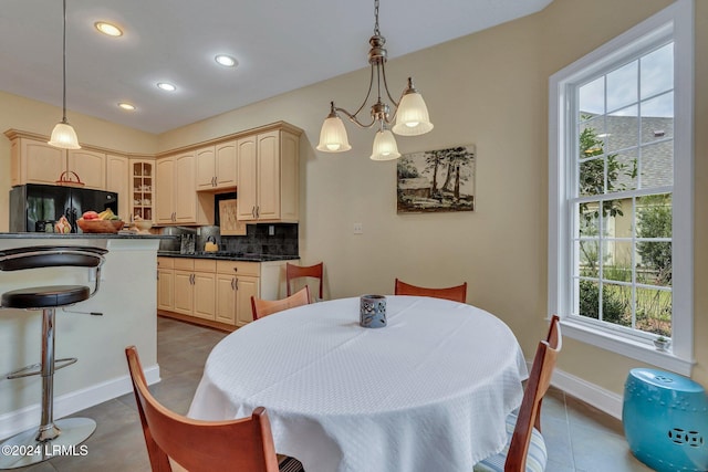 tiled dining room featuring an inviting chandelier and plenty of natural light