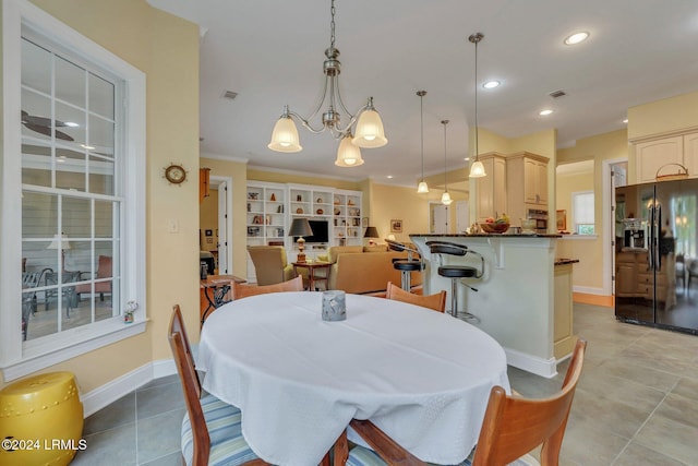 dining room featuring light tile patterned floors, crown molding, and a chandelier